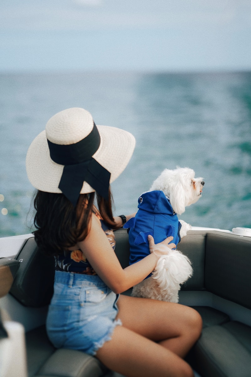 A woman sitting on a boat holding a white dog