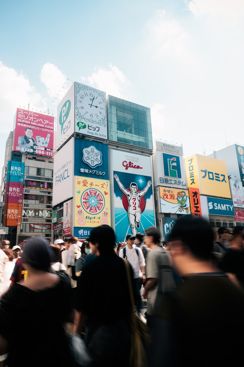 A crowd of people walking down a street next to tall buildings